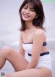 A woman in a white and blue bathing suit sitting on the beach.