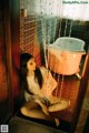 A woman sitting on the floor in front of a bathtub.