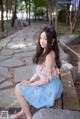 A woman sitting on a bench in a park.