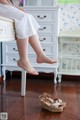 A woman sitting on top of a dresser with her feet up.