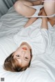 A woman laying on top of a bed in a white shirt.