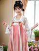 A woman in a pink and white hanbok poses for a picture.