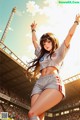 A woman in a soccer uniform standing in front of a stadium.