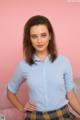 A woman in a blue shirt and plaid skirt posing for a picture.