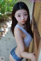 A young woman leaning against a wooden fence.