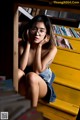 A woman sitting on a yellow bench in front of a book shelf.