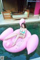 A woman in a bikini sitting on an inflatable flamingo in a pool.