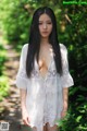 A woman in a white dress standing in the woods.