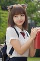 A young woman in a school uniform holding a red mailbox.