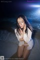 A woman sitting on the beach with her hands on her face.