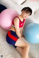 A young woman sitting on the floor next to two exercise balls.