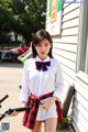 A woman in a white shirt and red plaid skirt standing next to a bike.