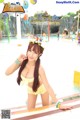 A woman in a yellow bikini posing in a water park.