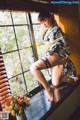 A woman in a kimono sitting on a window sill.